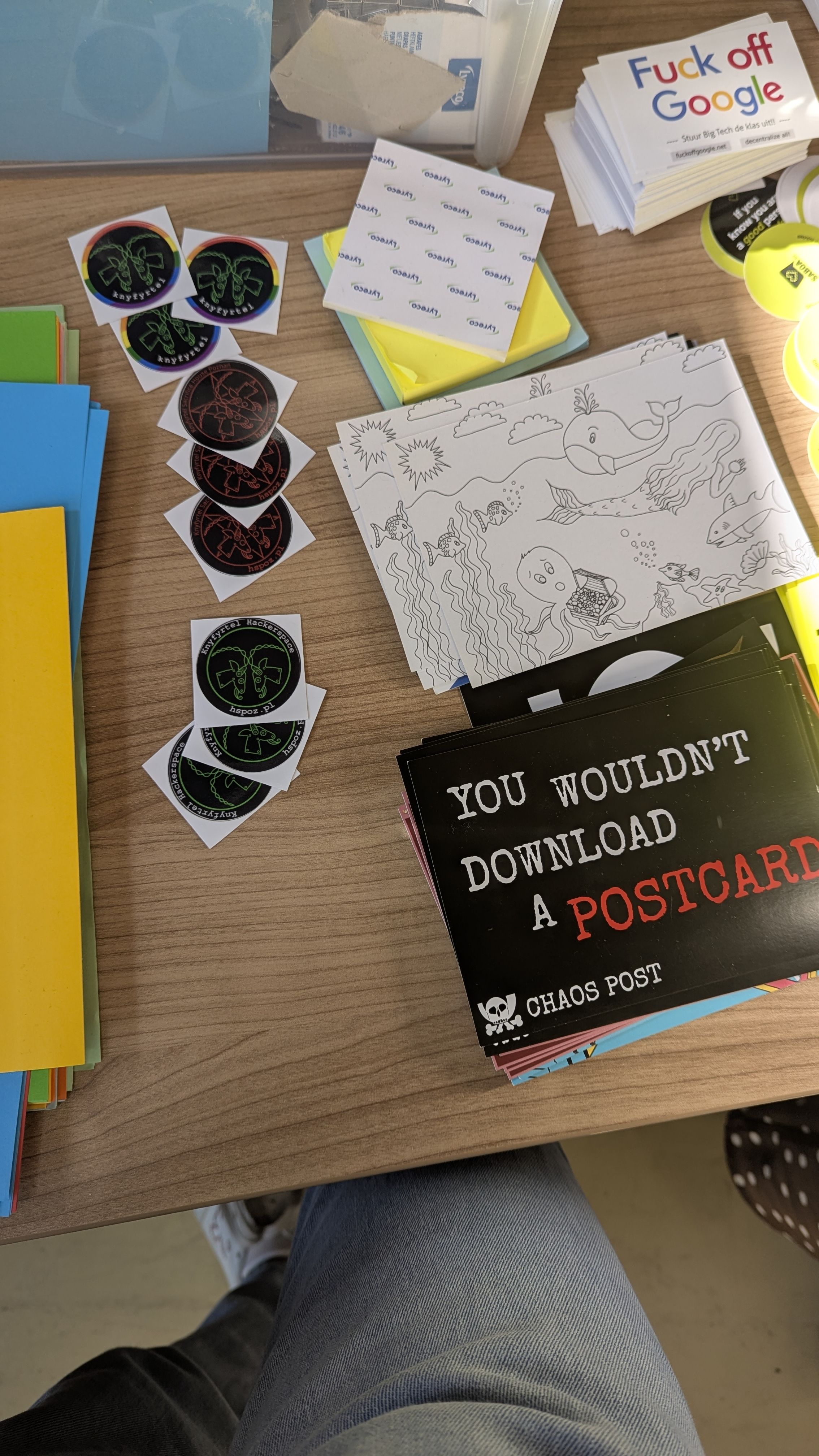 a table with a bunch of stickers and postcards, including Knyfyrtel hackerspace ones