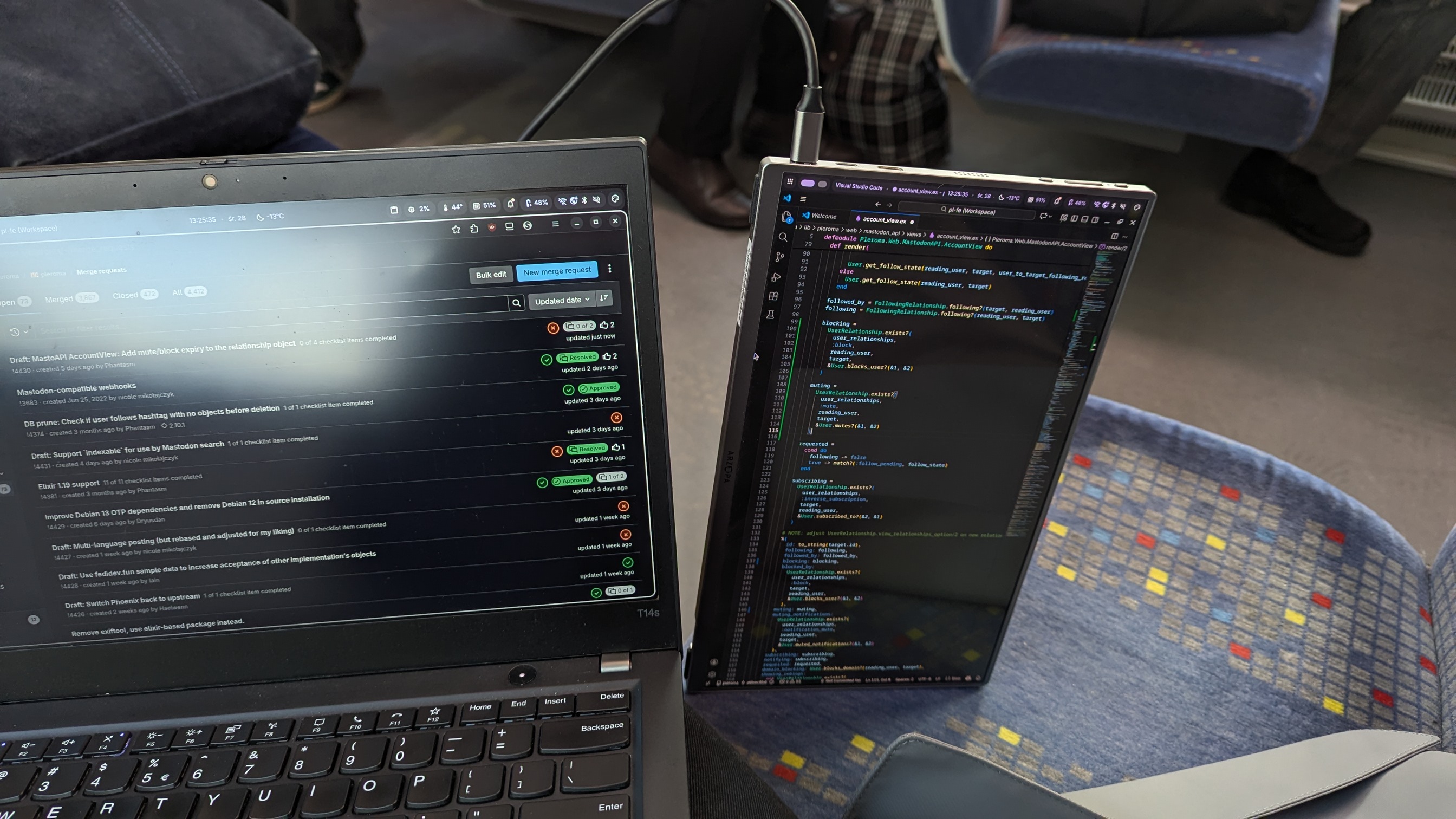 doing Pleroma dev in a train. there’s a laptop with Pleroma GitLab page and a portable screen with VS Code next to it