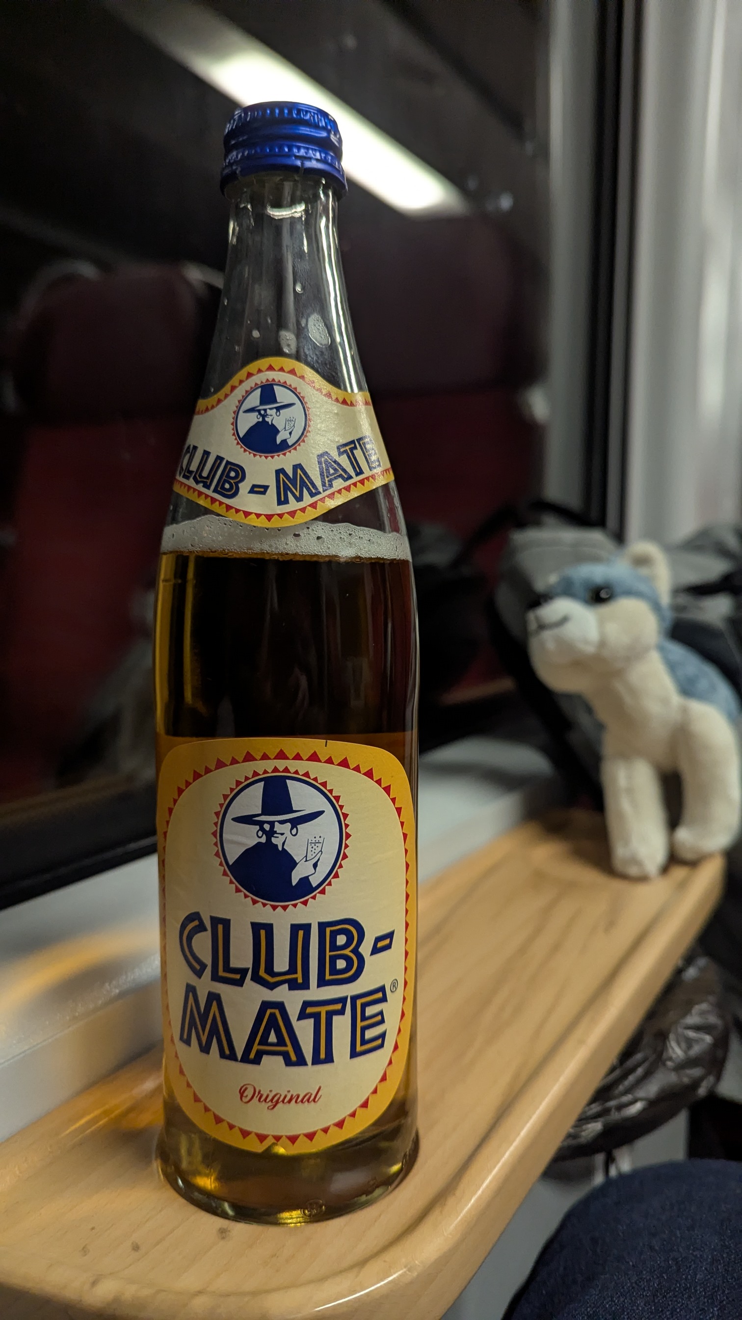 na pierwszym planie butelka club mate, zdjęcie w pociągu